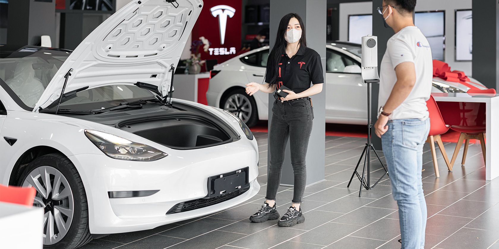 Persona che guarda una Tesla Model 3 in una concessionaria.