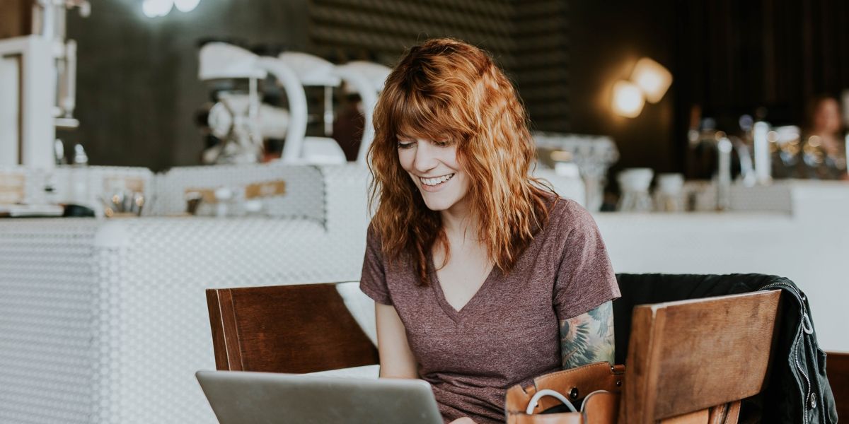 Una donna seduta in un bar, al lavoro sul suo computer portatile.