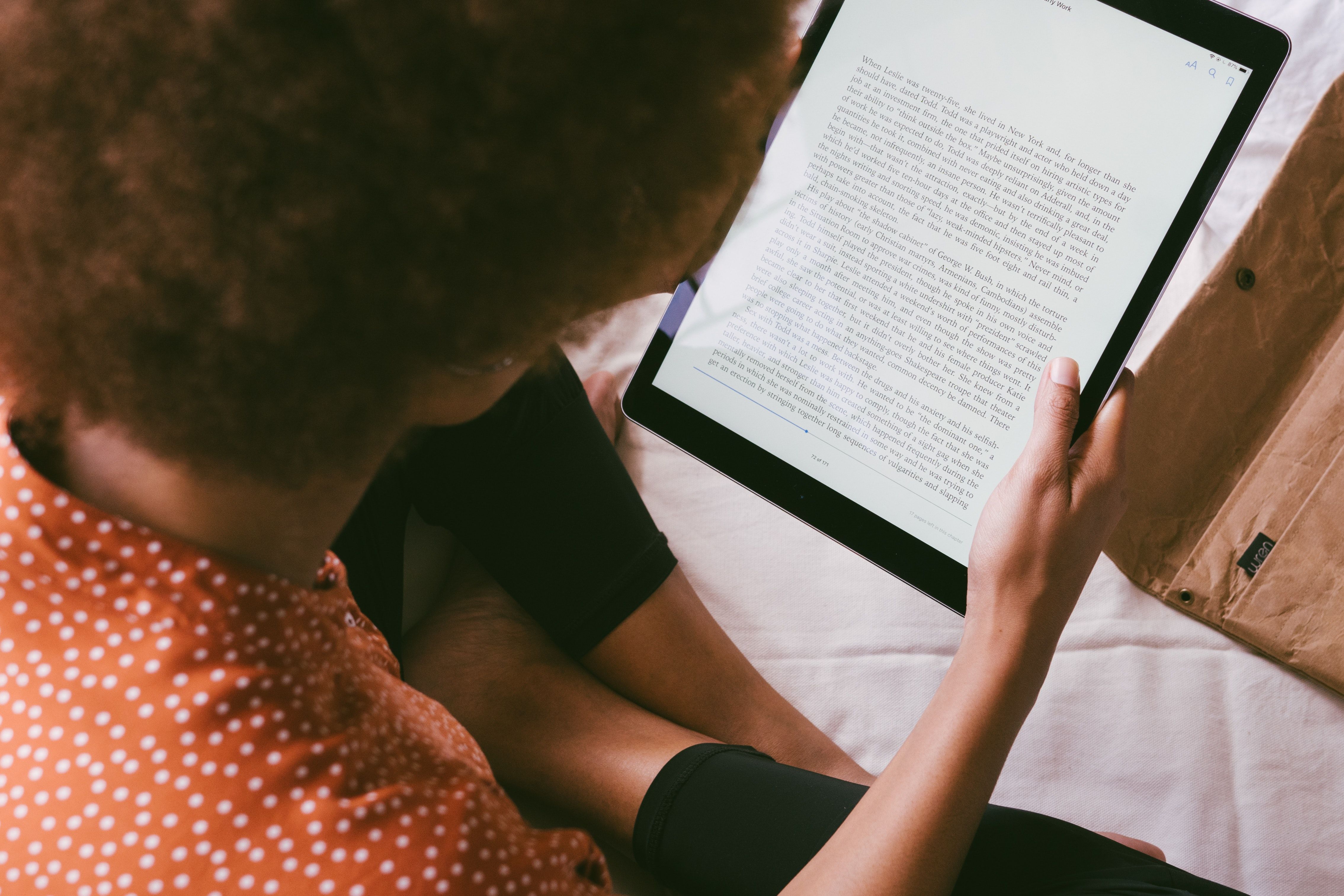 Una foto dall'alto che mostra una donna seduta che legge un ebook sul suo iPad