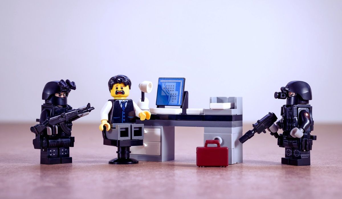 Polizia Lego che circonda una persona Lego seduta a una scrivania.