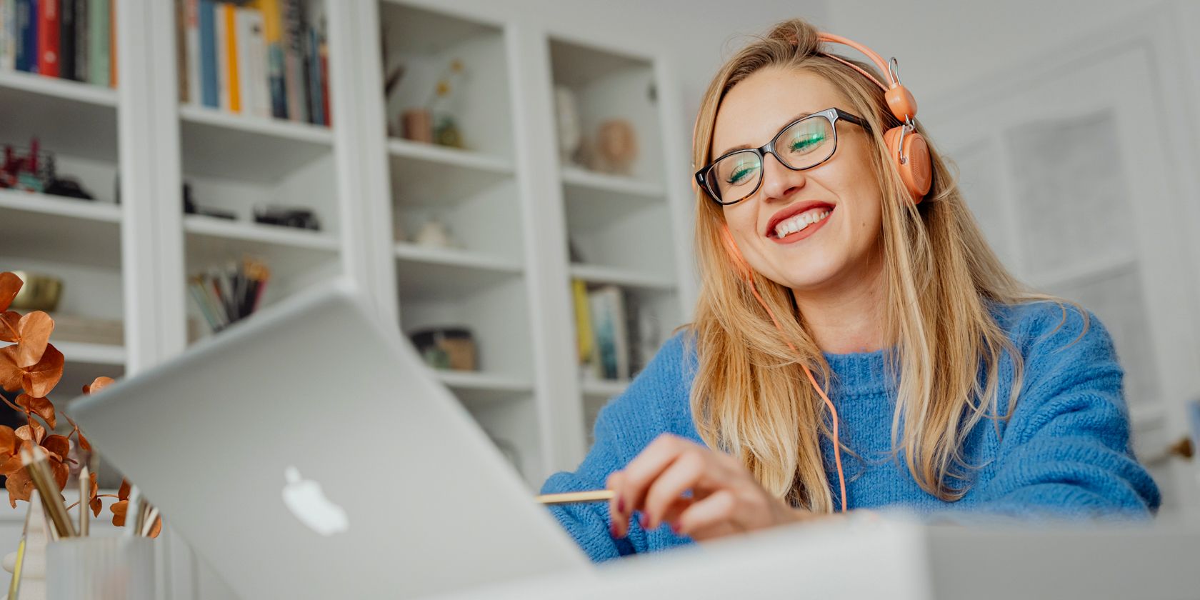 Una donna felice che ascolta le cuffie mentre utilizza un computer portatile