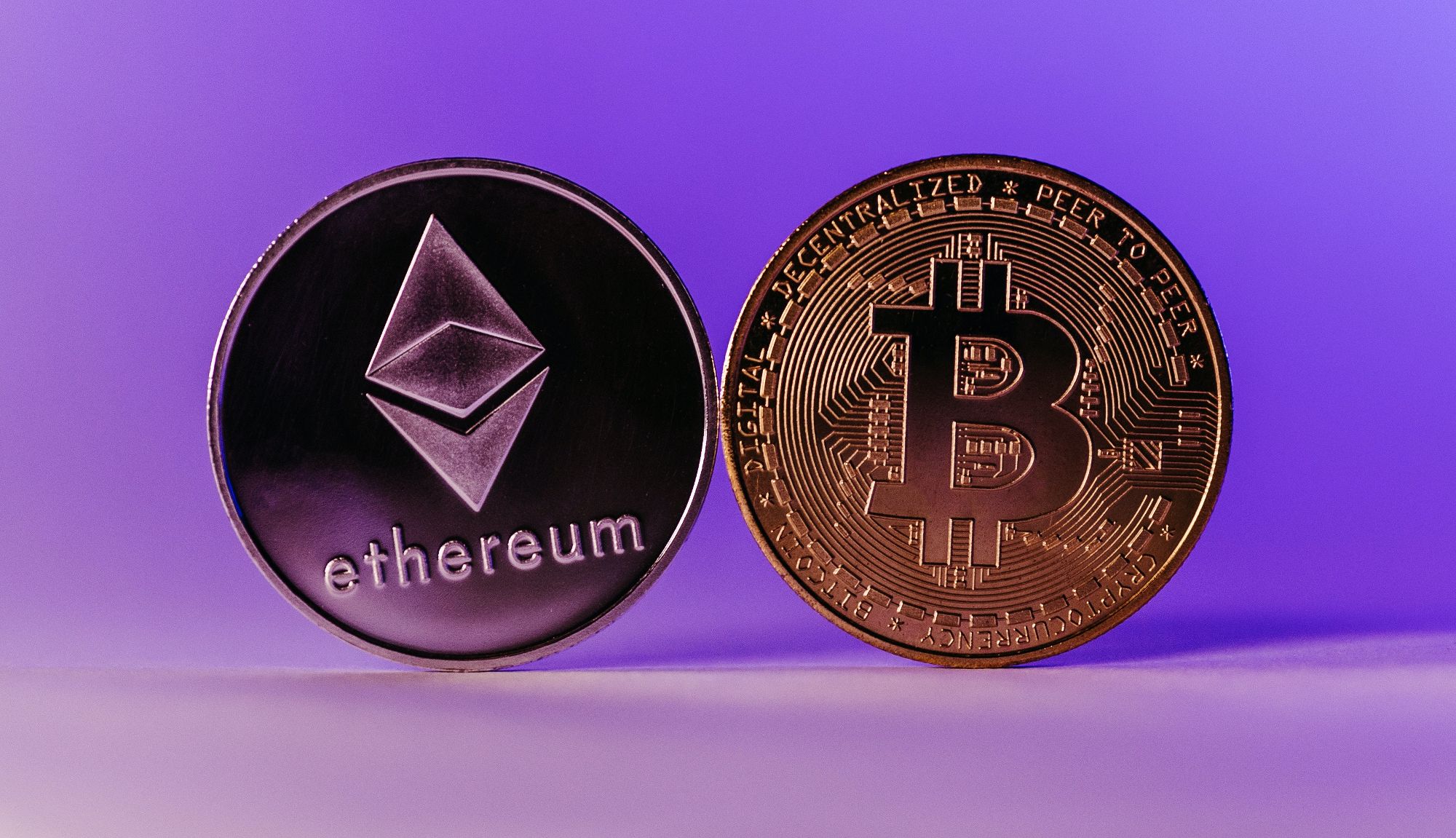 monete ethereum e bitcoin affiancate su sfondo viola