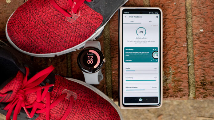 Google Pixel Watch accanto a un telefono Android che mostra un punteggio di recupero giornaliero Fitbit.
