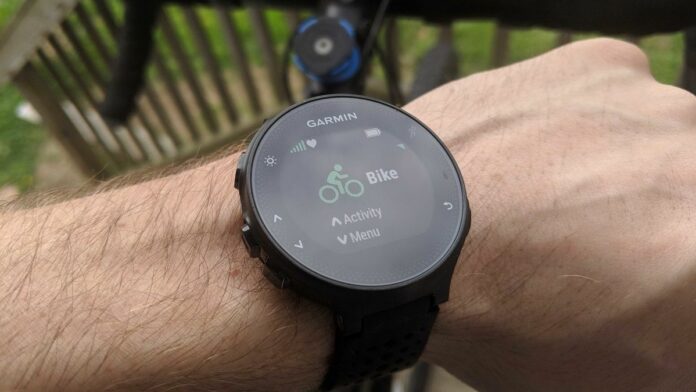 Starting an activity on the Garmin Forerunner 235, worn in front of a bike visible in the background..